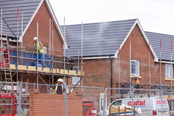 A bricklayer and two other construction workers perform tasks at the site