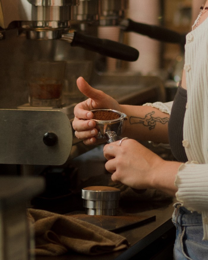 A man preparing ground coffee by a machine at Elysian Coffee Roasters