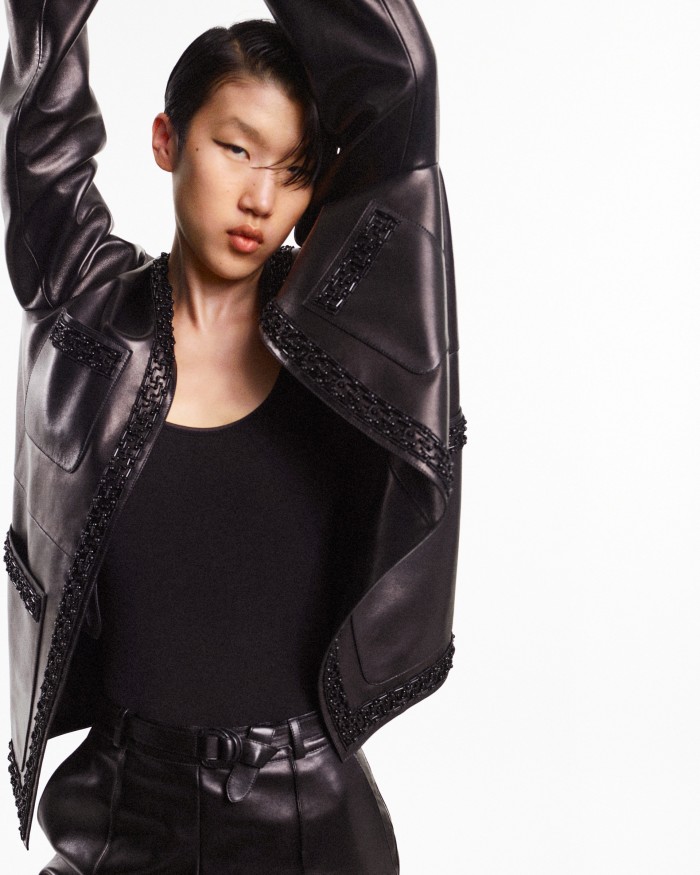 Jiashan Liu wears glossy leather jacket with glass and wooden bugle and horn bead-embroidered borders inspired by the Faubourg Greek frieze, made of leather from a previous collection, POA. Clothing throughout by Hermès