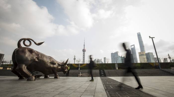 Pedestrians walk past the Bund Bull statue in Shanghai