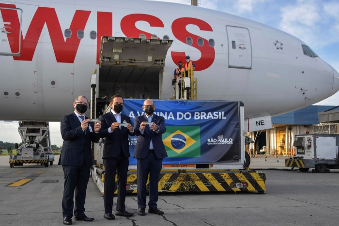 Brazilian officials at São Paulo airport next to a container carrying vaccines from China