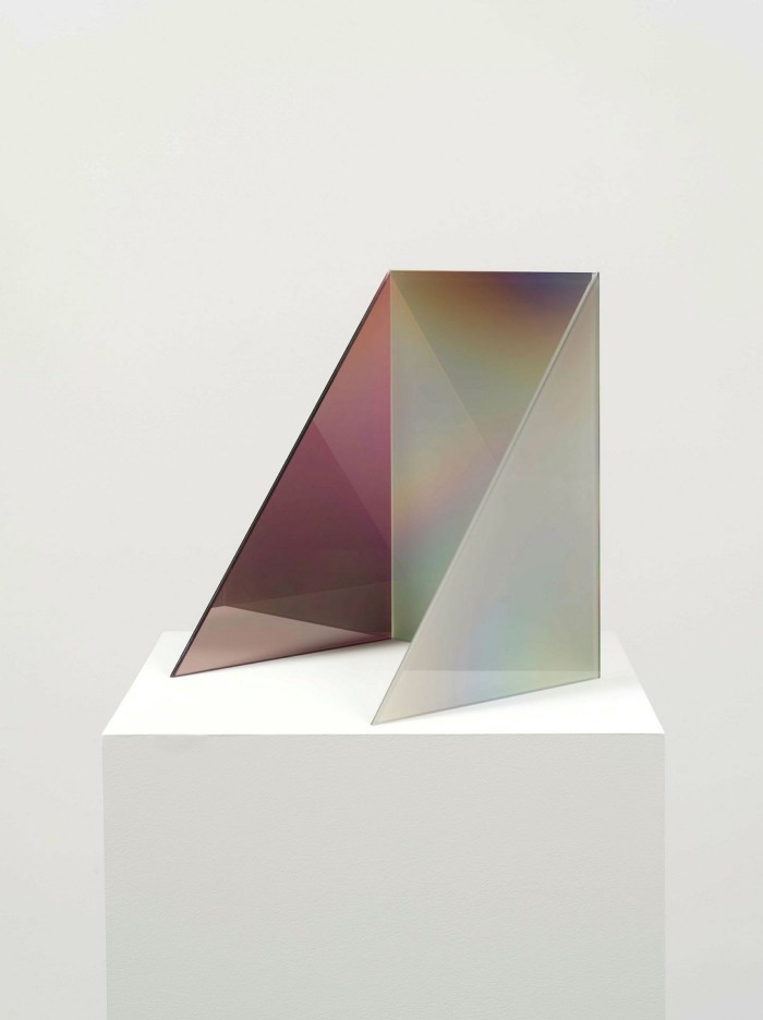 A small sculpture of a glass pane with two triangles at 90 degrees. The pane and one triangle are greyish, the other triangle plum