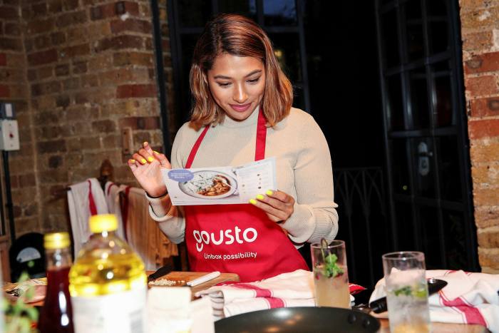 Woman wearing a red Gousto apron about to prepare a meal