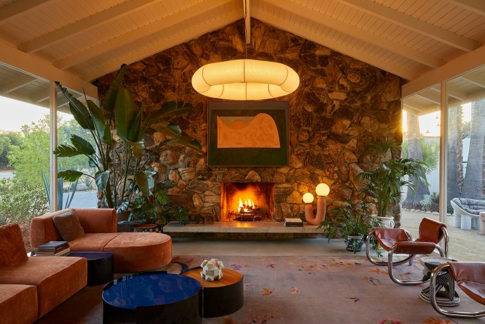 A 1960-style sitting room with a fireplace in a rough-stone wall at Capri Hotel