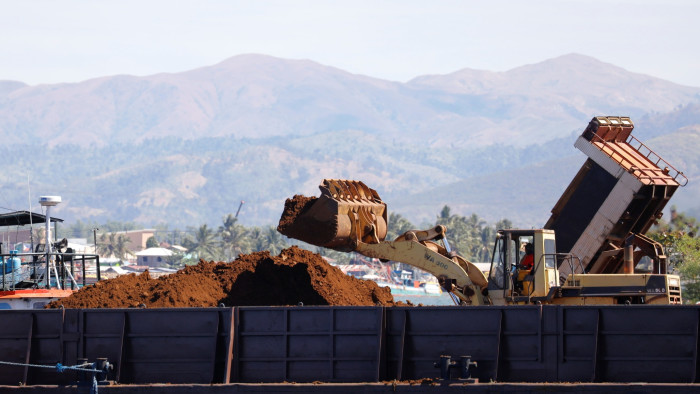 A back hoe loads soil containing nickel-ore minerals into a barge in the mining town of Sta Cruz Zambales in northern Philippines