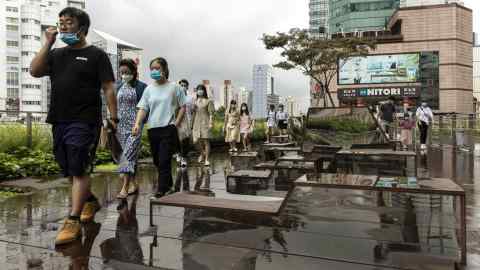 Pedestrians wearing protective masks walk along a promenade near a shopping mall in Shanghai, China