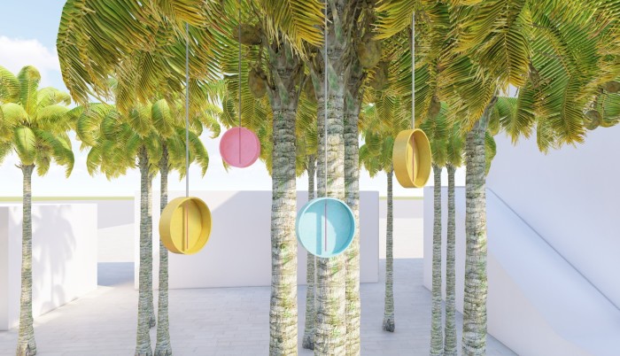 Several palm trees sit in a white courtyard with four bottle cap-like objects hanging from the near tree — two in yellow and one in pink and another in blue