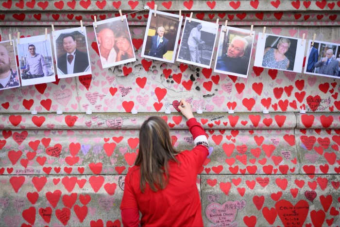 A woman leaves notes below photos of people who died of Covid-19