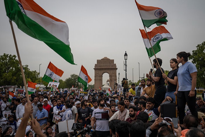 Indian wrestlers, right, Bajrang Punia, Vinesh Phogat, and Sakshee Malikkh stand on a police barricade as they speak to their supporters near landmark India Gate monument during a protest march against Wrestling Federation of India President Brijbhushan Sharan Singh