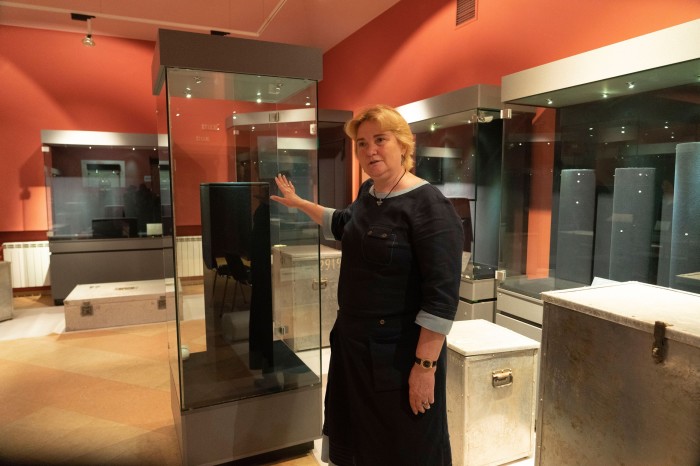 woman showing empty display cases of a museum