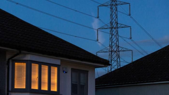 A light on at a home near an electricity transmission tower