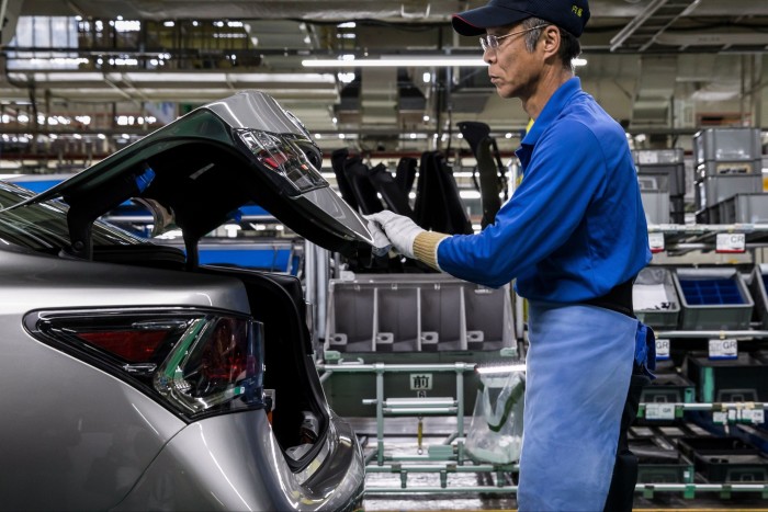 A worker assembles a vehicle on the production line of a factory