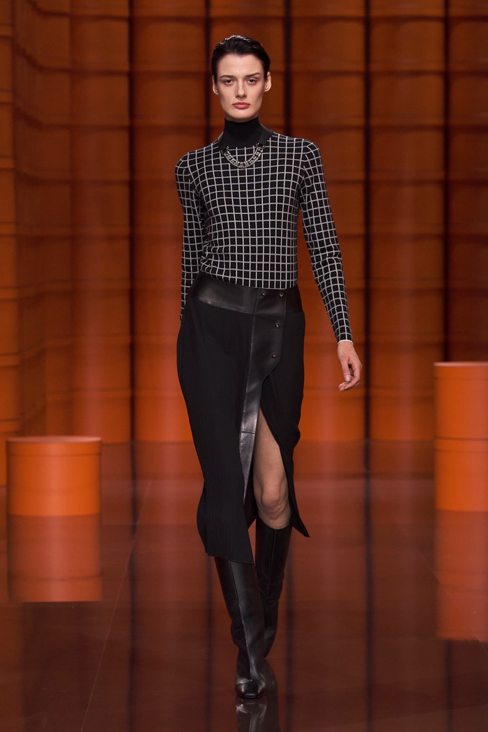 Hermès Tattersall-inspired silk and cashmere jumper, plissé wrap skirt, black Swift calfskin and palladium-finish metal necklace, and black calfskin boots from the house’s AW21/22 collection