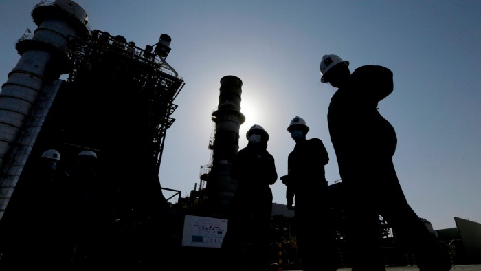 Saudi Aramco engineers walk in front of a gas turbine generator at Khurais oil field