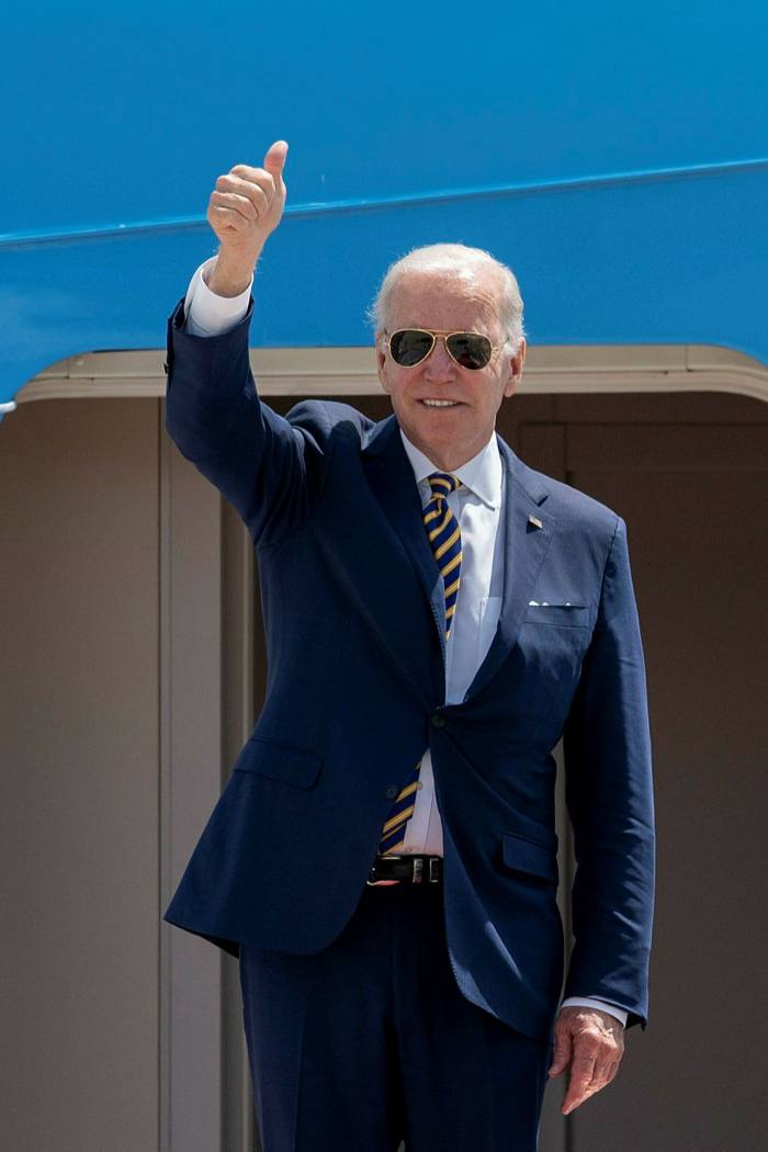 President Joe Biden, in sunglasses, gives the thumbs-up as he stands at the top of aircraft steps