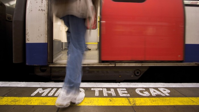 photo of a person about to enter a train. The words ‘mind the gap’ is on the train platform