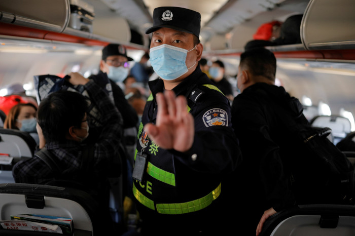 A Chinese police officer orders journalists off a plane in Xinjiang, where members of the local Uyghur population have been interned