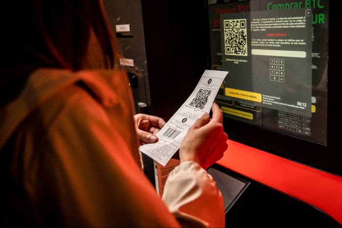 A customer holds a receipt from a bitcoin ATM in a Barcelona kiosk