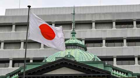 The Japanese flag flutters over the Bank of Japan head office building in Tokyo