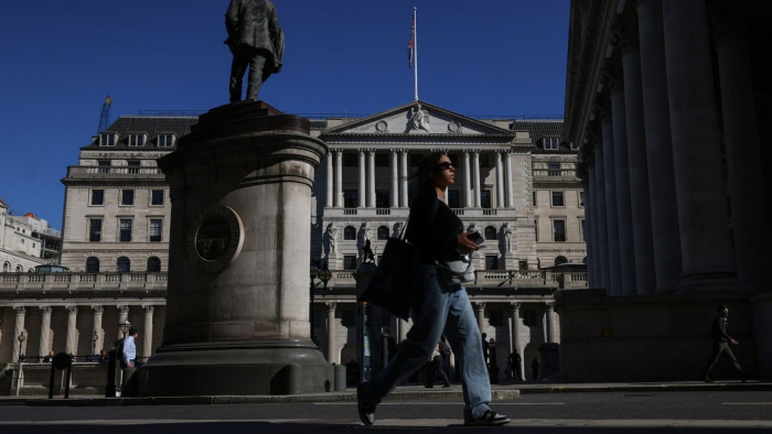 Pedestrians walk in front of the Bank of England building