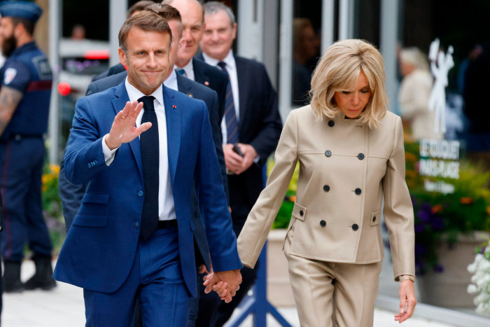 French President Emmanuel Macron, left, and his wife Brigitte leave the polling station after voting in the first round of parliamentary elections in Le Touquet, northern France 