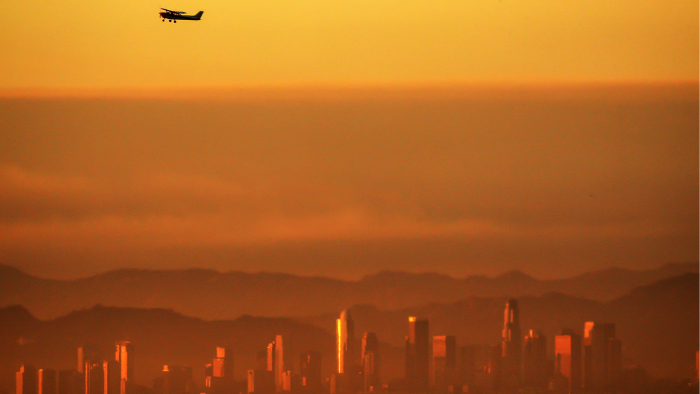 An airplane takes off from an airport in the sunset amid a smog