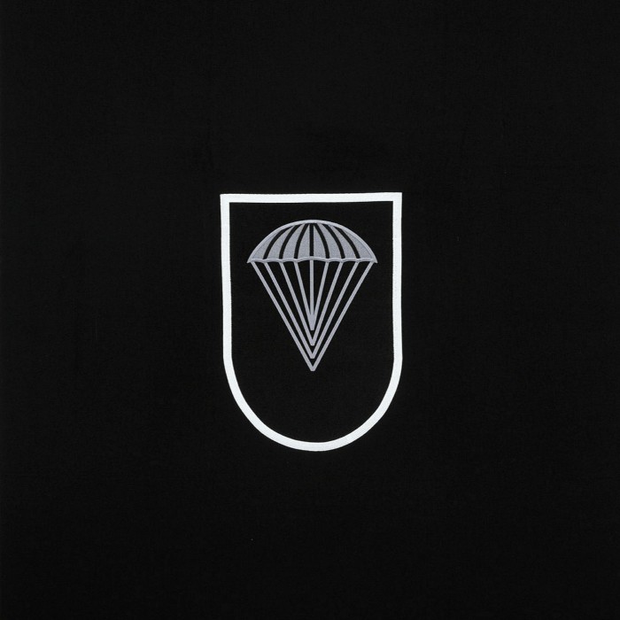 The same emblem now reduced to a parachute in a white line