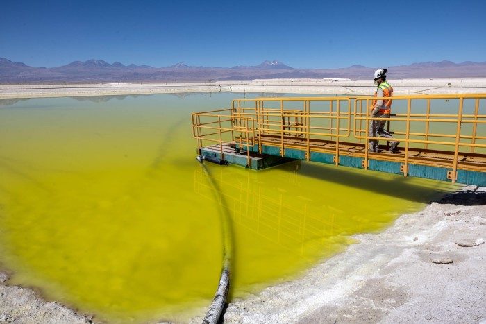 A lithium mine supervisor inspects an evaporation pond of lithium-rich brine in the Atacama Desert