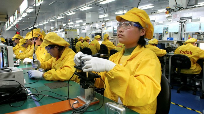 Factory workers assemble digital cameras on a production line in Shanghai