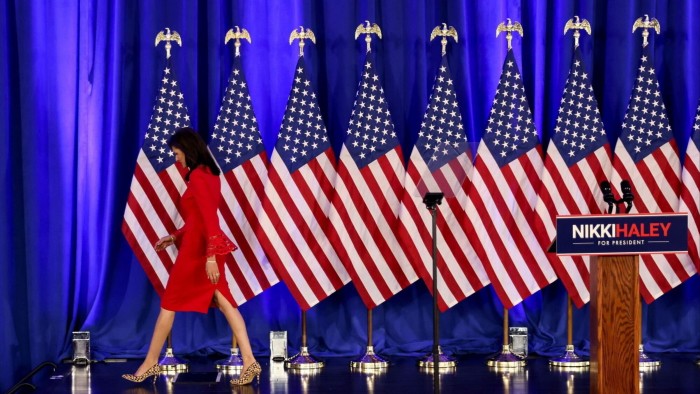 Nikki Haley walks past US flags, away from a podium featuring the words ‘Nikki Haley for president’