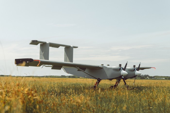 A flying vehicle with propellers, wings and tail fins in a field 