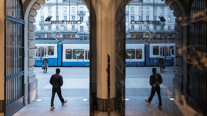 People walk in the front of the Credit Suisse bank at the tram stop Paradeplatz in the square’s center in Zurich