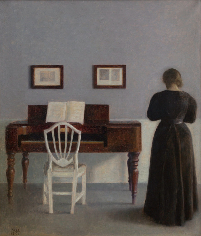 In a painting, a woman in a black dress stands on the right of a wooden piano displaying an open music book while facing a wall decorated with two frames
