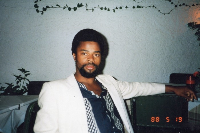 A photograph dated 1988 of Ben Okri in a white jacket and blue shirt