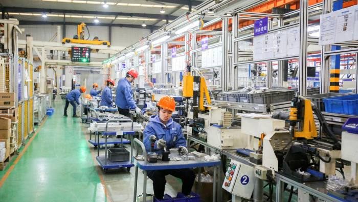Chinese workers wearing long-sleeved blue tops, black pants and hard hats at a manufacturing facility