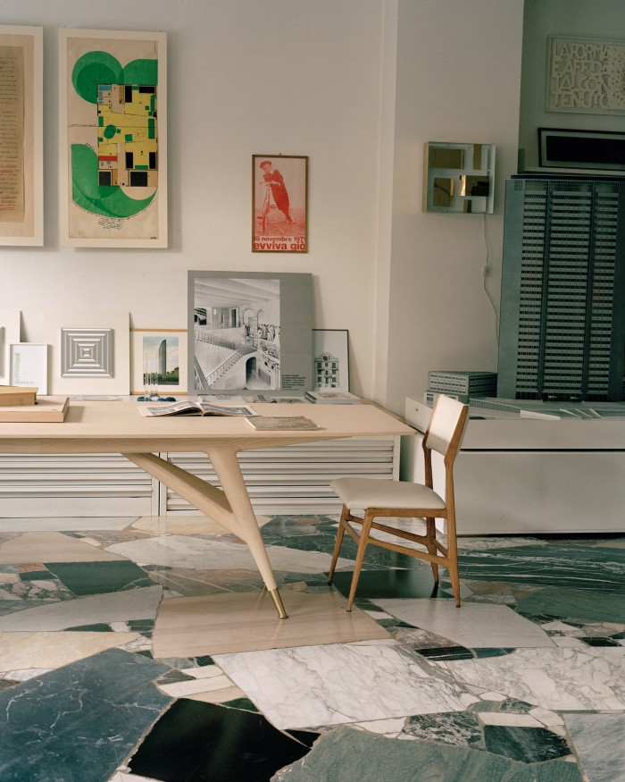 The main space in the Gio Ponti Archives, housed in Ponti’s Via Dezza studio, with a D.859.1 table, reproduced by Molteni&C, and a 687 chair, designed for Cassina. On wall (from left), a 1970 study for tall buildings, a poster printed for his 80th birthday party, the Quadro Luminoso lamp he designed for Arredoluce in 1957, and a model of the Pirelli Tower