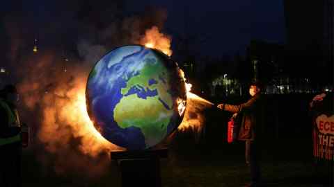 An environmental activist extinguishes a burning a model of the Earth during a climate protest