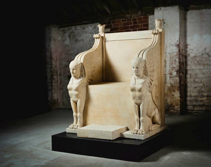 A large uncomfortable-looking throne made out of stone (the seat is at a right angle to the back). The arm rests descend into carved male sphinxes