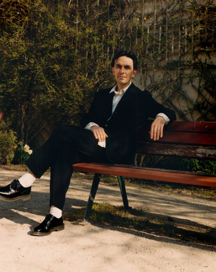 A man in dark suit reclining on a park bench