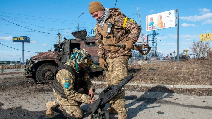 Ukrainian soldiers handle equipment from a damaged military vehicle after fighting in Kharkiv
