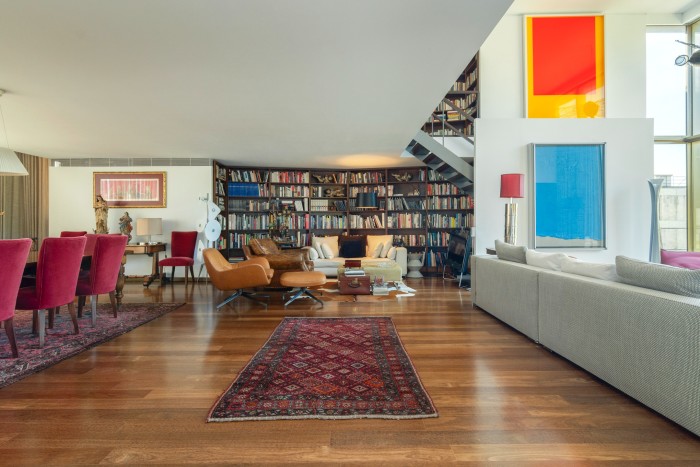 A large living area with built in bookshelves and double-height windows on one side