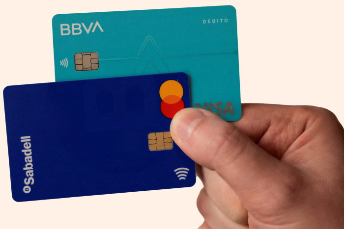 A man shows his debit cards from BBVA and Sabadell 