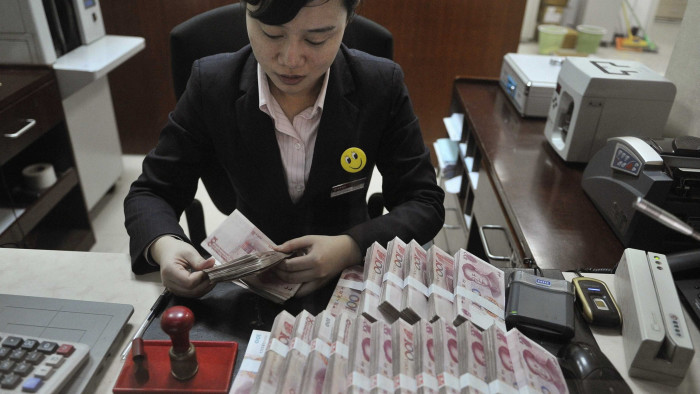 A clerk counts banknotes at a branch of China Merchants Bank