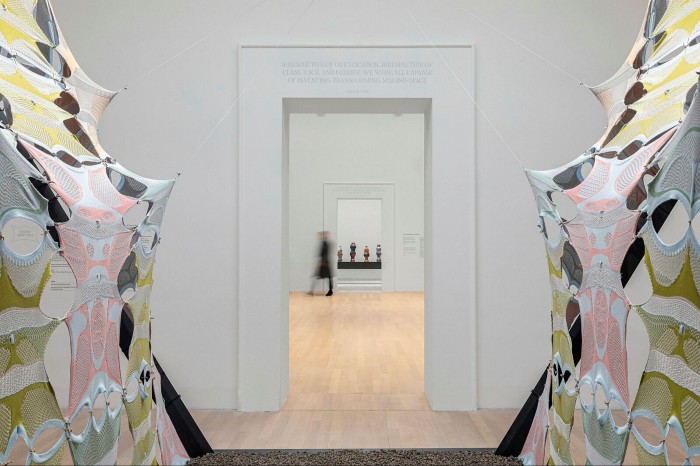 Yellow and pink fabric sculptures installed in an art gallery, with wall text by the US writer Bell Hooks