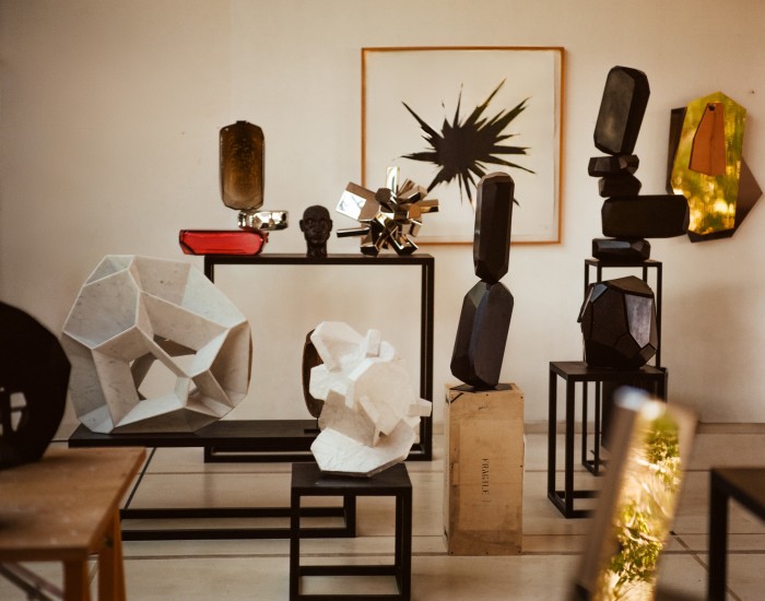Arik Levy’s studio, containing, on table from left: MicroRockFormationGlass, 2021; SelfPortrait, 2020; RockGrowth 44, 2015. On wall from left: WoodHeart 002, 2019; FacetPattern, 2014