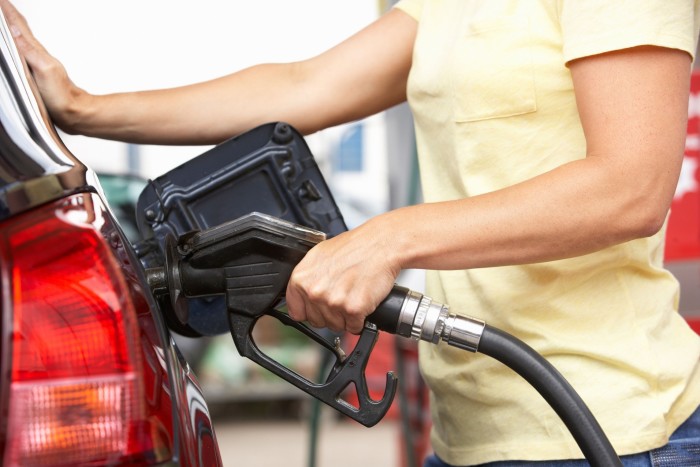 Female motorist filling car with diesel at petrol station