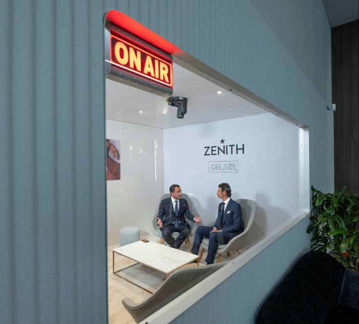 Two businessmen sitting inside a studio with the ‘On air’ sign turned on