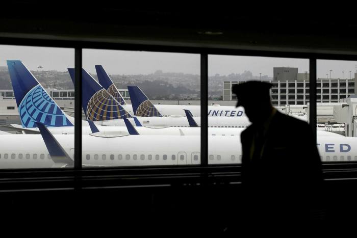 A pilot walks by United Airlines planes as they sit parked at gates at San Francisco International Airport on April 12, 2020