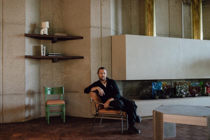 Lionel Jadot in the lobby. Beside him is the Lionel Jadot x Chair Doctor chair which has a leather woven seat by Charles Schambourg. The lamp is by Pascale Risbourg x Atelier Haute Cuisine