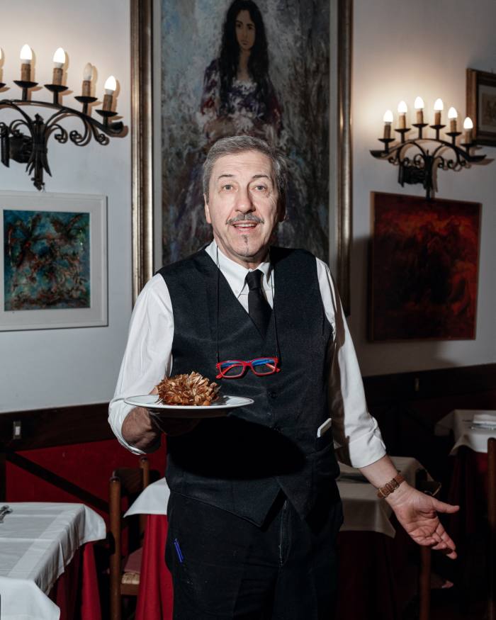 Fernando Manella, a waiters at Giggetto al Portico d’Ottavia, holding a plate of Jewish-style artichoke